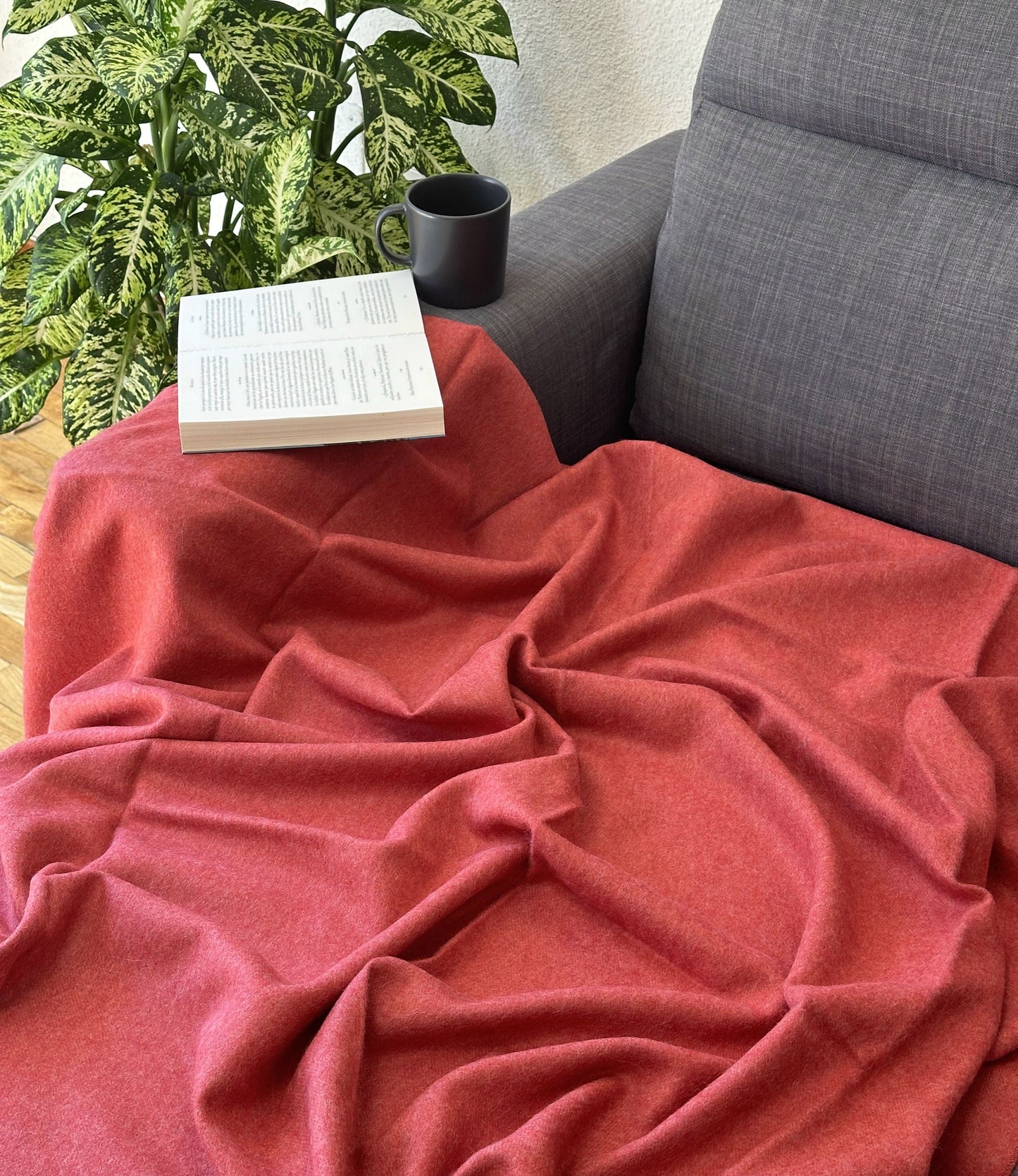 Plaid rouge en alpaga sur canapé, ajoutant confort et élégance à votre décoration intérieure avec une chaleur naturelle et une texture douce.