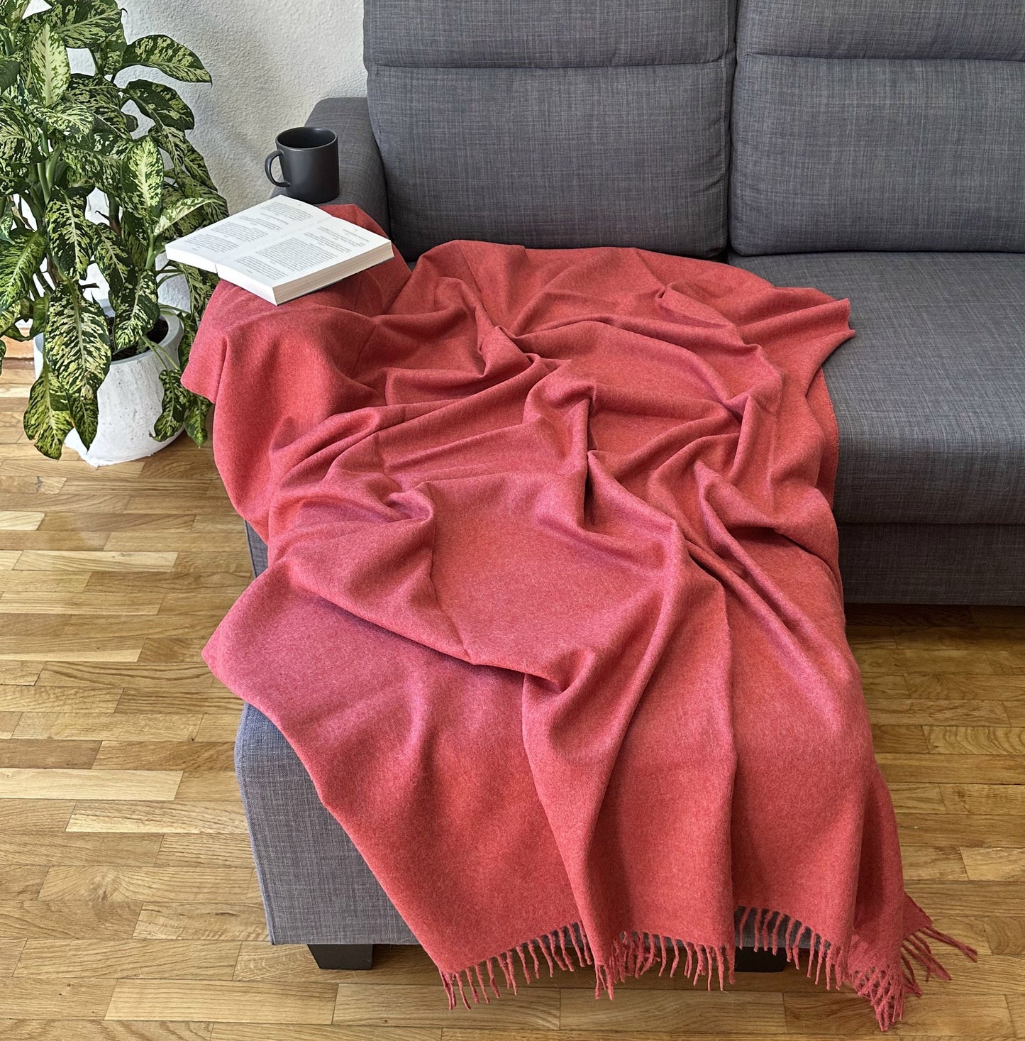 Luxurious red wool blanket styled on a sofa, perfect as a cozy throw for bed or living room.