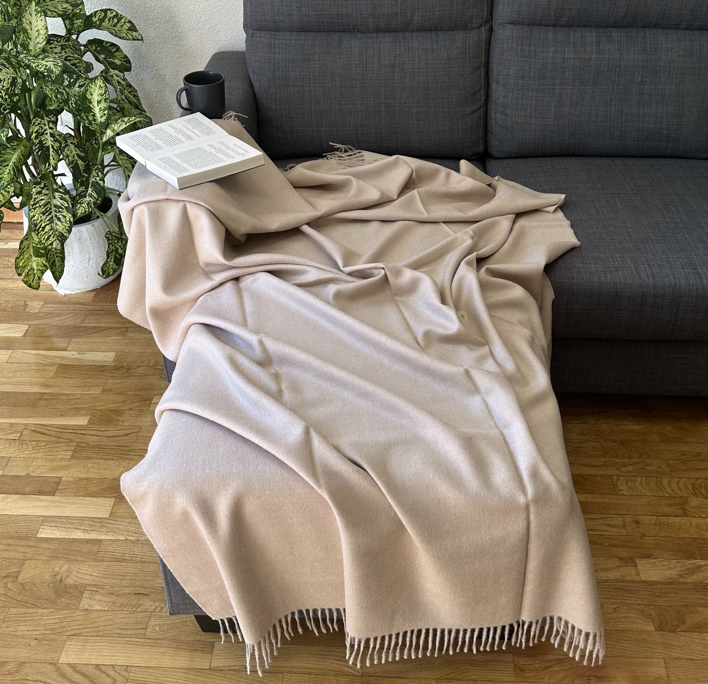 Luxurious beige alpaca blanket draped on a sofa, perfect as a cozy throw for bed or living room.